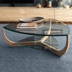 a glass coffee table sitting on top of a blue rug in front of a tv