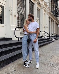 a man and woman standing next to each other in front of a building with stairs