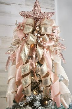 a christmas tree decorated with pink and gold ribbons