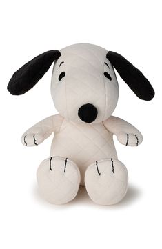 a white stuffed dog with black ears sitting