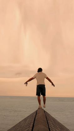 a man standing on top of a pier next to the ocean