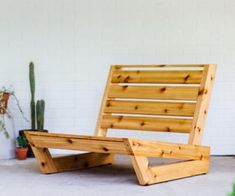 a wooden chair sitting in front of a white brick wall next to a potted plant