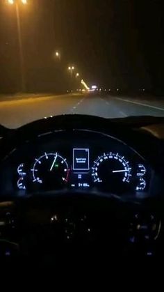 the dashboard of a car at night on a highway with lights and speedometers