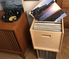 an old record player is sitting on top of a dresser next to a stack of records