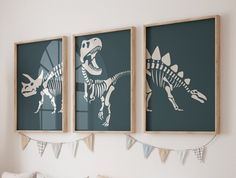 two framed dinosaur prints on the wall above a bed