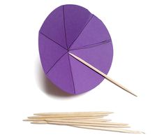 an origami circle with two sticks sticking out of it and another piece of paper next to it