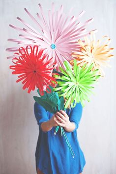 a woman holding three paper flowers in her hands