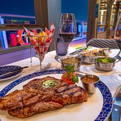 a steak is served on a blue and white plate at a restaurant with wine glasses