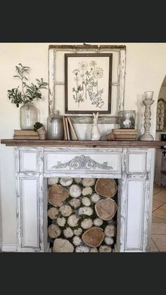 a fireplace with logs stacked on top of it in front of a mirror and vases