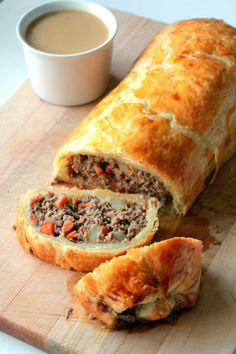 a meat filled pastry cut in half on a cutting board