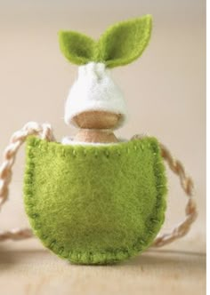 a stuffed animal in a green purse on a string