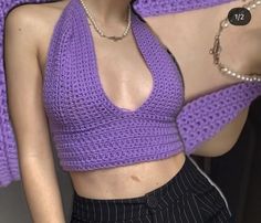 a woman wearing a purple crop top and black pants with her hand on her hip