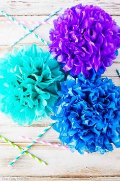 three blue and purple flowers with straws next to each other on a wooden table