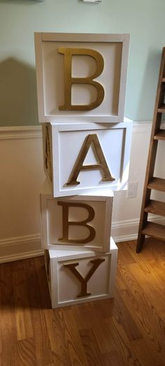 three wooden blocks with letters that spell out the word baby in gold and white on them