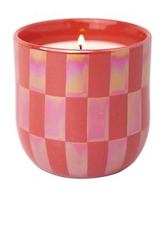 a pink and yellow checkerboard candle in a red glass bowl on a white background