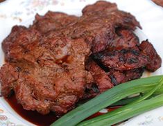 a plate with meat and green onions on it