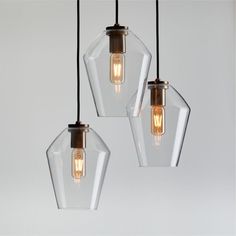 three clear glass pendant lights hanging from a ceiling