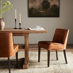 a dining room table with two chairs and a vase on the table next to it