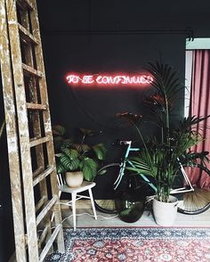 a bicycle is parked in front of a neon sign that says to be comfy