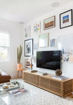 a living room filled with furniture and framed pictures on the wall above a flat screen tv