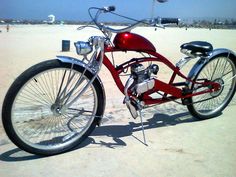 a red motorcycle parked on top of a sandy beach