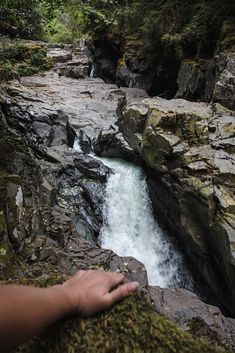 a hand reaching out over a small waterfall