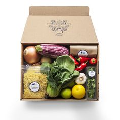 two cardboard boxes filled with different types of vegetables and fruits next to each other on a white background