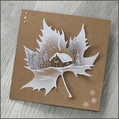 a card with an image of a leaf and a house in the snow on it