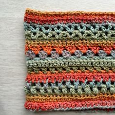 a crocheted dishcloth with multicolored stripes on it sitting on a table