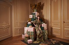 a woman sitting on top of a pile of wrapped presents in front of a wall