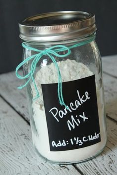 a glass jar filled with powdered mix on top of a wooden table next to a chalkboard