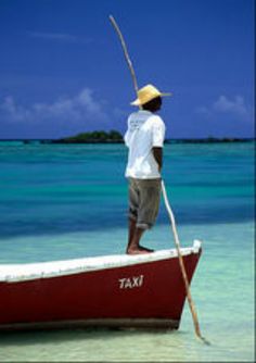 a man standing on top of a red boat in the middle of the ocean with a fishing pole