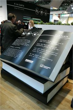 an open book sitting on top of a wooden floor next to a table filled with people