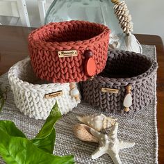 three knitted baskets sitting on top of a wooden table next to a starfish