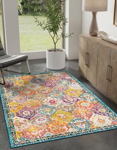 a colorful area rug in a living room with a chair and potted plant next to it