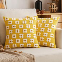 two yellow and white pillows sitting on top of a couch next to a pillow case