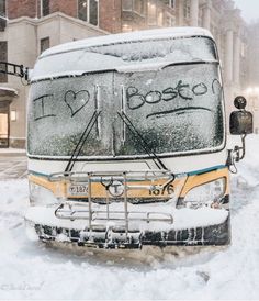 a bus is parked on the side of the road covered in snow and has graffiti written on it