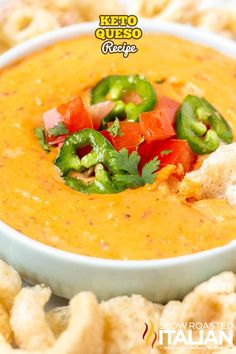 a white bowl filled with soup and vegetables on top of crackers in front of it