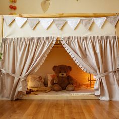 a teddy bear sitting on top of a bed in a room with white drapes