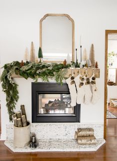 a fireplace decorated for christmas with stockings hanging from the mantel and evergreen garland on top