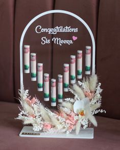 a display with candles and flowers in it on top of a brown tableclothed surface