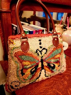 a handbag with a butterfly on it is sitting on a chair next to books