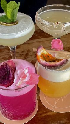 three different types of cocktails sitting on top of a wooden table next to each other