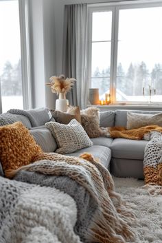 a living room filled with lots of furniture next to a large window covered in blankets