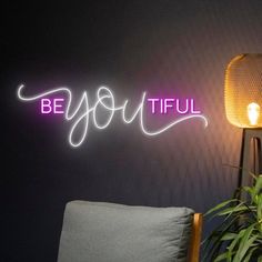 a neon sign that reads be you tiful next to a lamp on a table