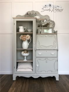 a white china cabinet with flowers on top