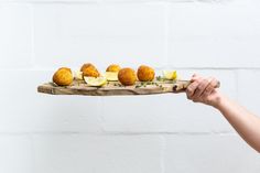 a person holding a wooden tray with food on it and lemon slices in the middle