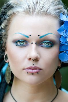 a woman with blue makeup and flowers in her hair