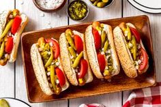 four hot dogs on buns with pickles, tomatoes and jalapenos