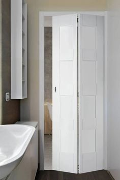 a bathroom with a sink, mirror and open door to the room that is white